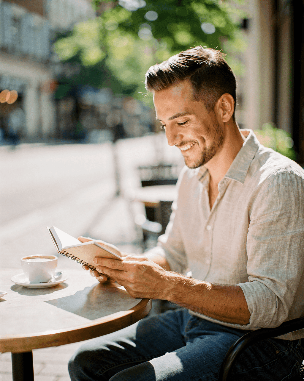 A trader smiling at a sunny café table, writing in a notebook