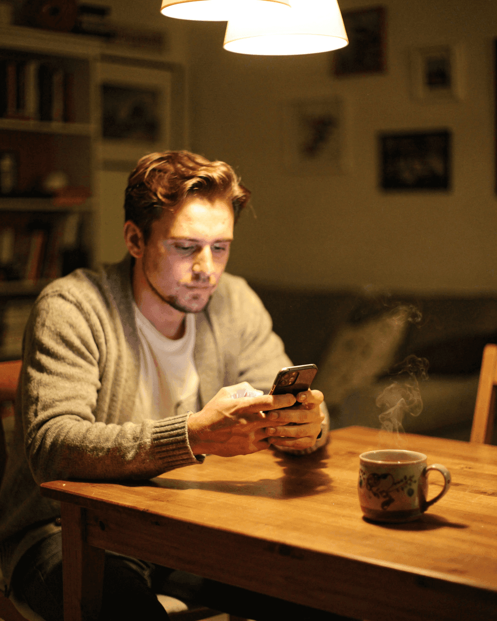 A trader at home on a Sunday evening checking his phone at the table, waiting for the forex market to open